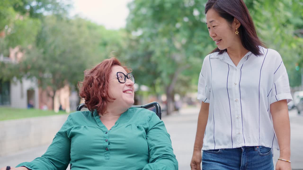 Two women, one in a wheelchair, enjoying a walk and conversation outdoors