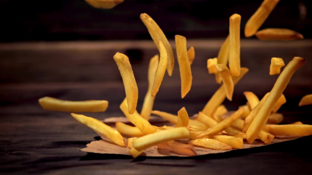 Golden French Fries Pouring and Falling onto a Rustic Wooden Table