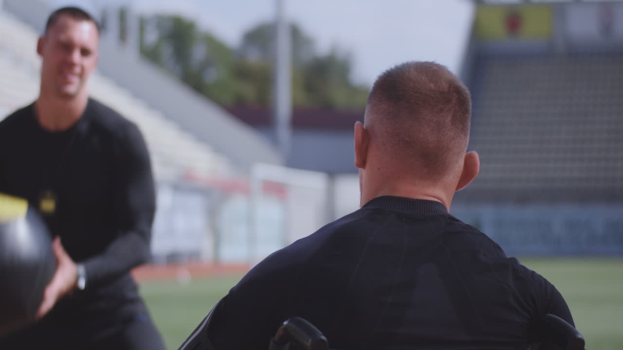 Wheelchaired Athlete and Trainer Throwing Medicine Ball Medium Shot of a Wheelchaired Athlete and his Trainer Working out with a Medicine Ball