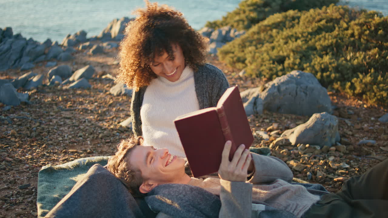 Relaxed couple reading novel aloud marine nature closeup. Man lying woman knees
