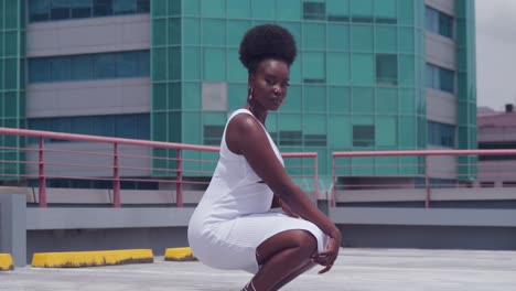 a young black girl in a white dress is on a rooftop, with the city spread out below