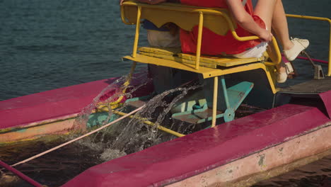las cuchillas del catamarán rocian agua de mar clara. madre e hija turistas mueven los pedales del transporte acuático deslizándose en movimiento. estilo de vida activo y recreación