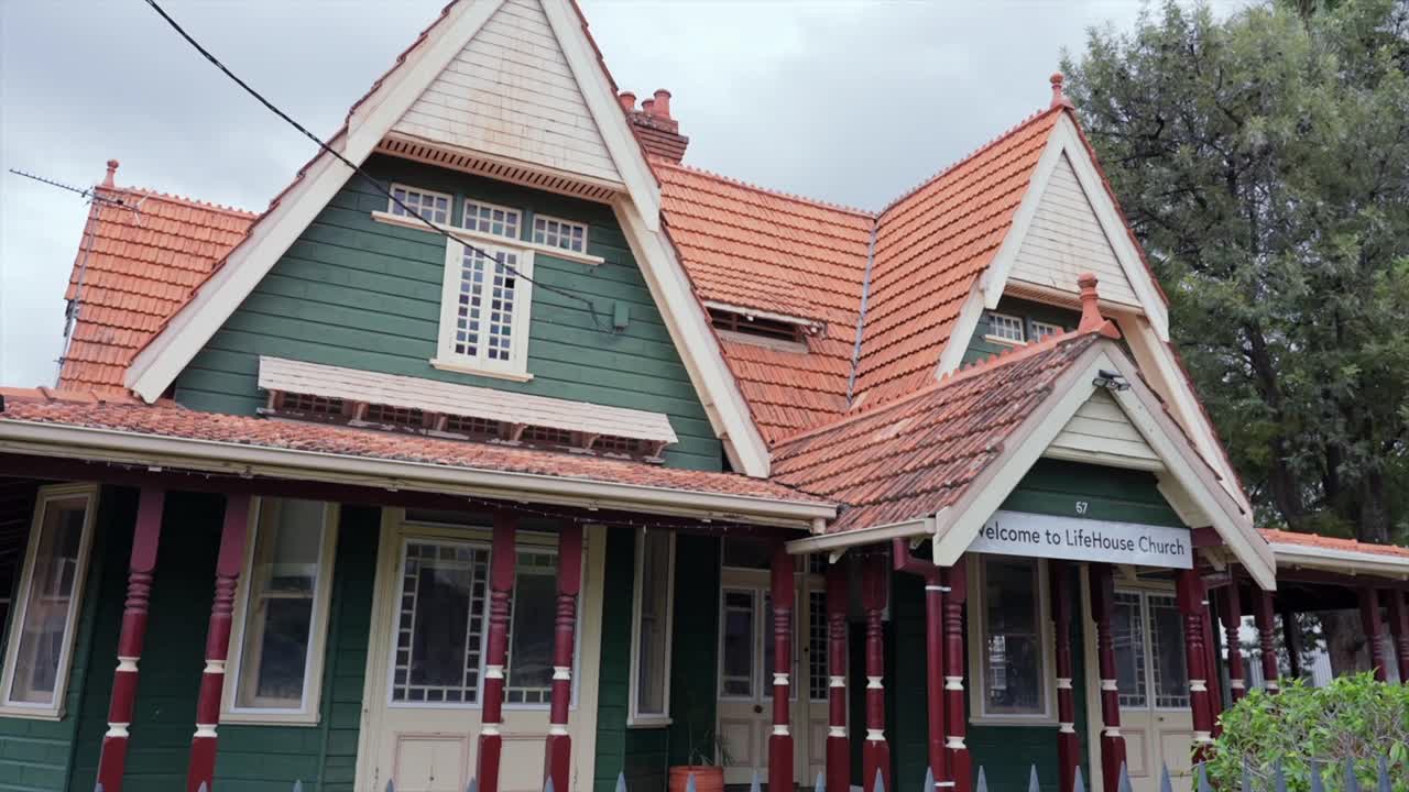 Heritage-style church building in Moree with steep gabled roof, timber detailing and green-and-cream exterior, filmed from street level on an overcast day