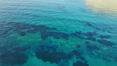 aguas claras de color turquesa sobre arrecifes de coral frente a la isla de corfú, grecia, tomada desde arriba, océano sereno