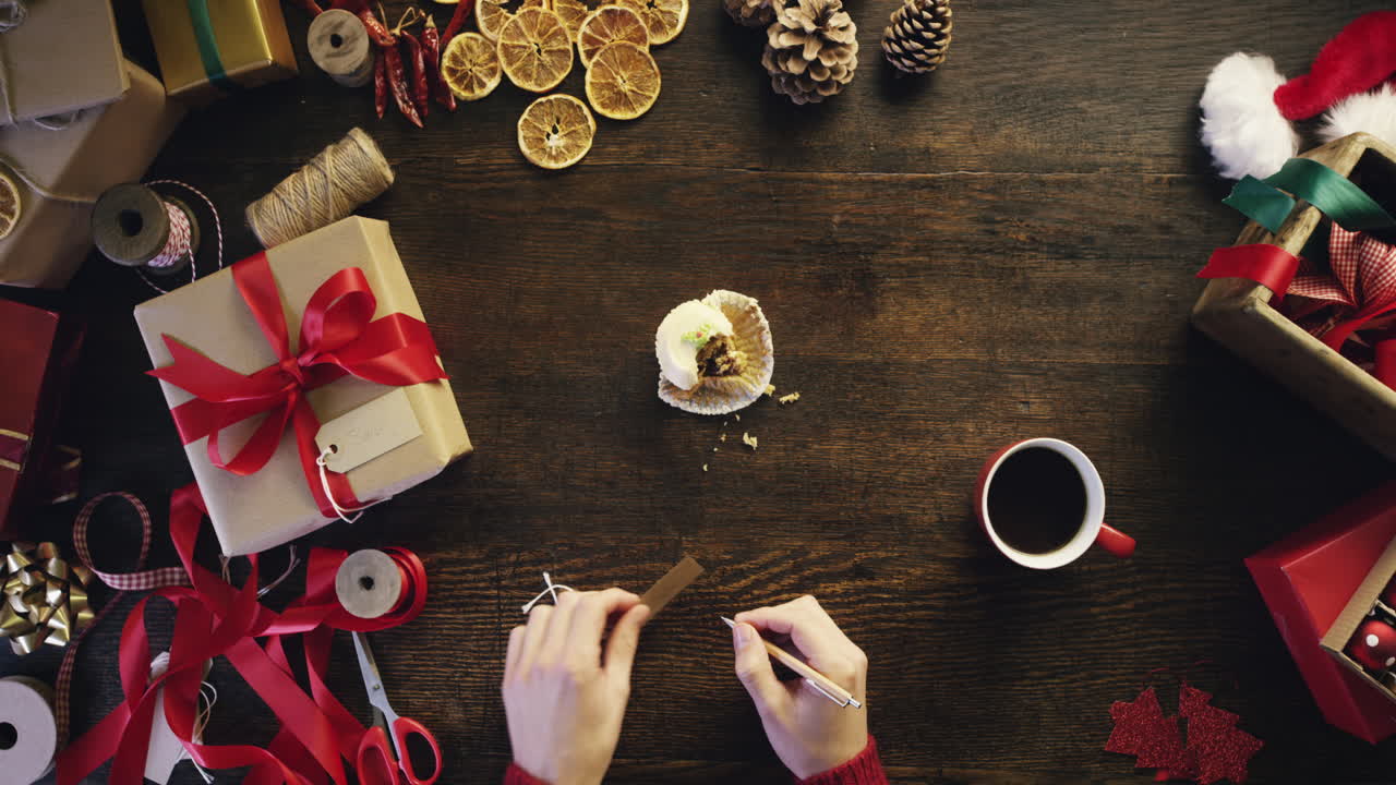 vista superior manos de navidad escribiendo nombre en tarjeta de regalo para regalos en escritorio de madera desde arriba - dragón épico rojo