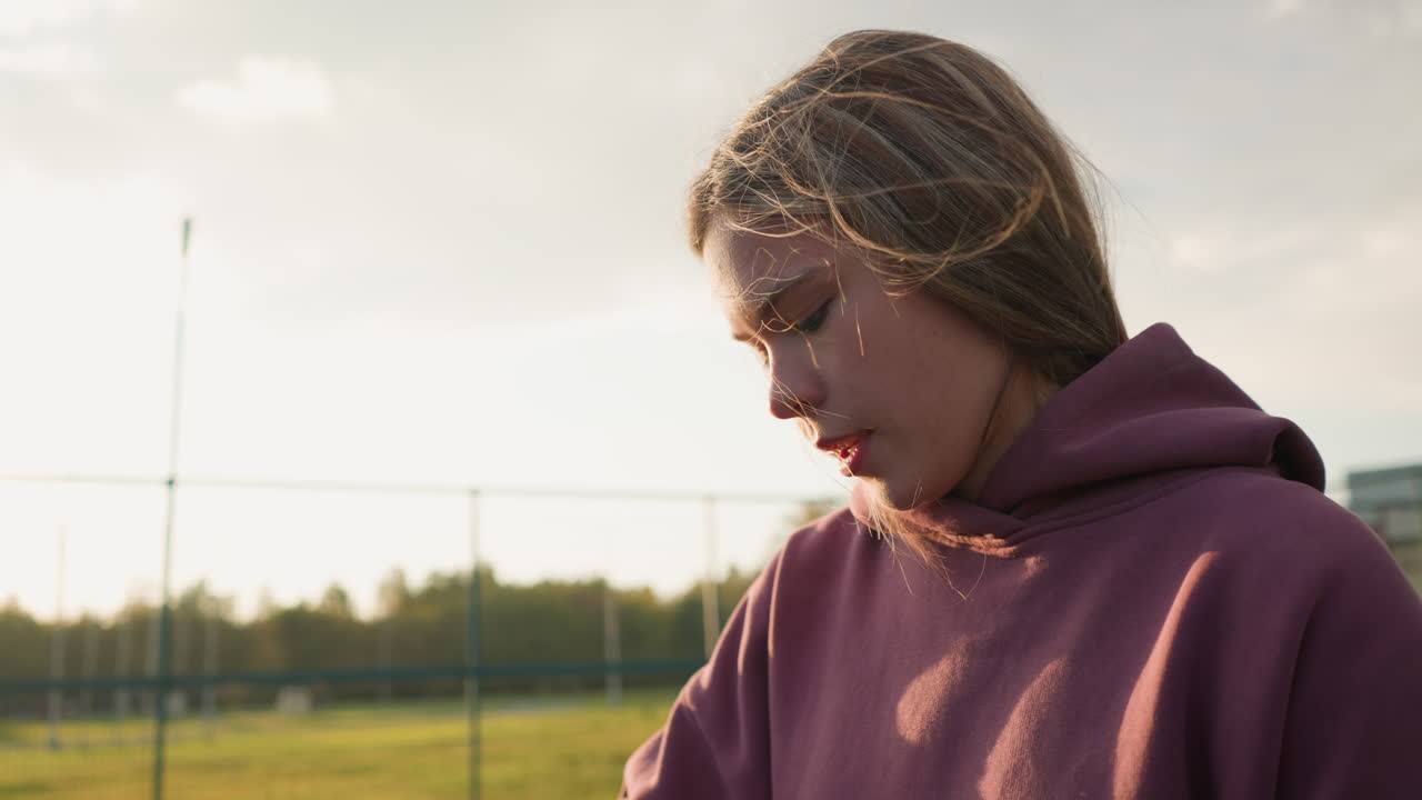 Close-up de uma mulher jogando vôlei ao ar livre com a luz do sol criando um brilho no plano de fundo, com o cabelo balançando ao vento e cercada por vegetação
