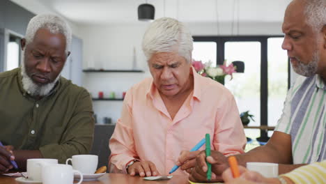 personas mayores felices y diversas bebiendo té y jugando al bingo en el hogar de ancianos