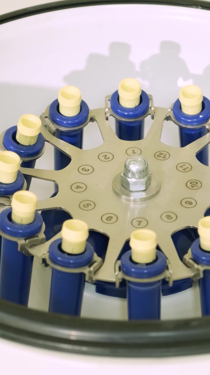 Primo piano di una centrifuga da laboratorio che gira e si ferma con provette.