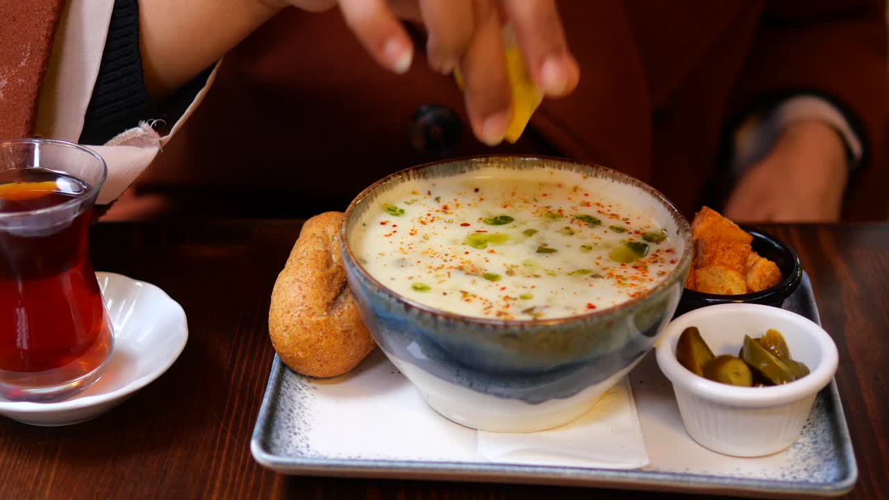 mujer exprimiendo limón en un tazón de sopa turca