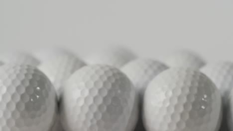 close up of golf balls on white background, copy space, slow motion