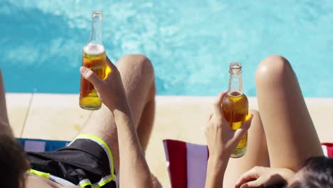 pareja relajándose en la piscina con cervezas