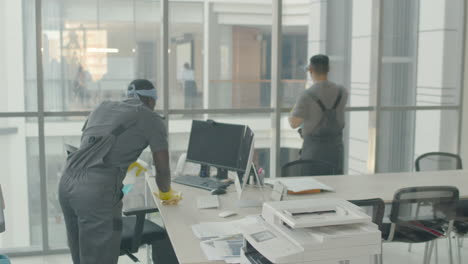 and arabic cleaning man cleaning a desk inside and windows panes inside an office