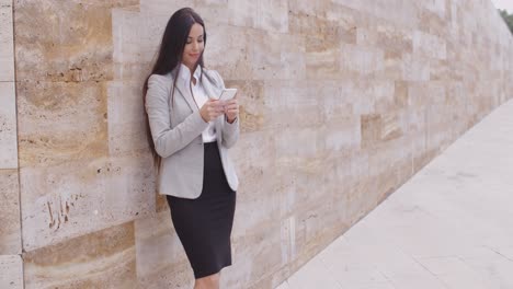 female worker texting and leaning against wall