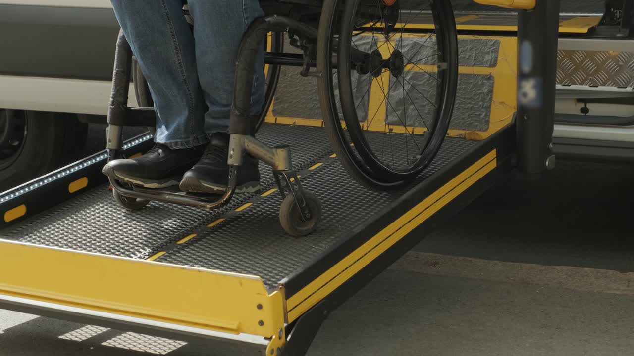 A man in a wheelchair on a lift of a vehicle for people with disabilities. Lifting equipment for people with disabilities - man in wheelchair near the vehicle