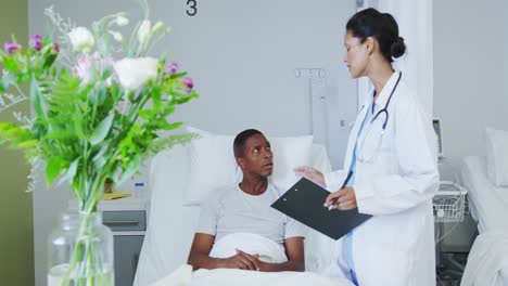 front view of african american female doctor talking with male patient in ward at hospital