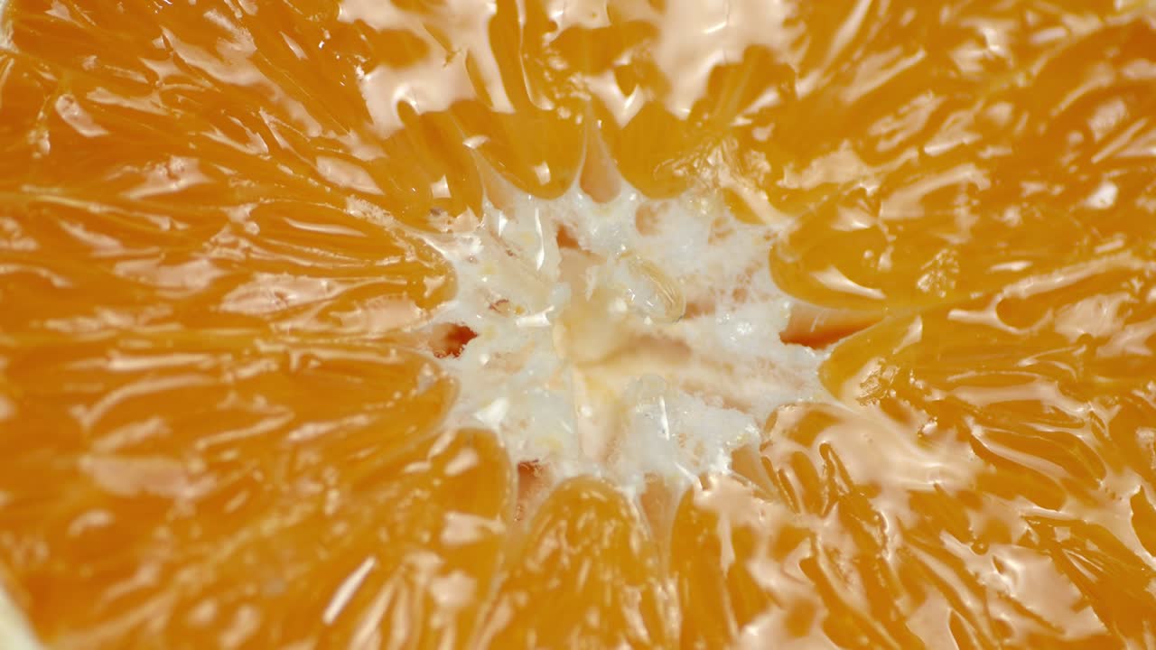 Slice of orange dripping juice. Macro background.