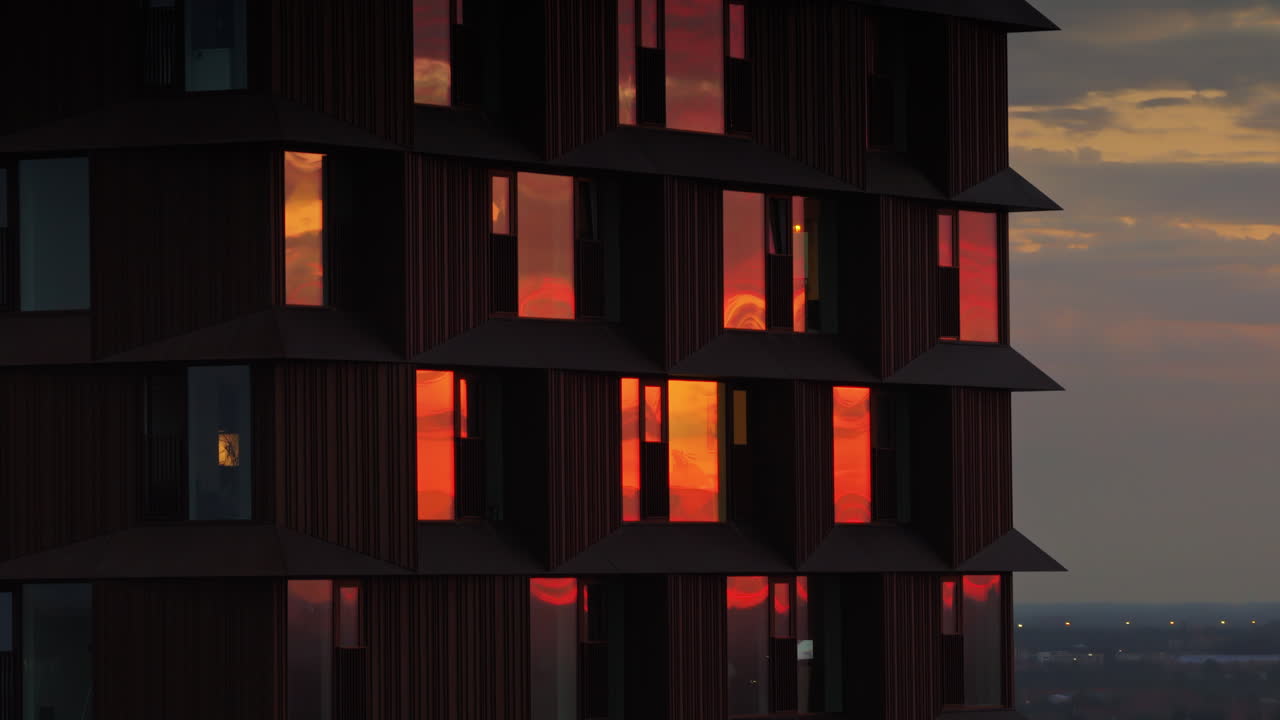 Aerial drone view of Copenhagen's Domus Vista skyscraper with fiery sunset reflections in its windows