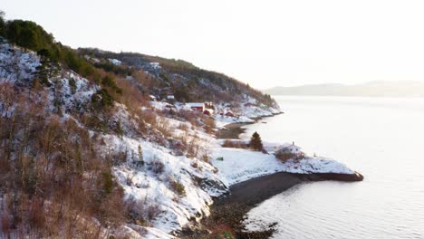 picturesque view of snowy mountains with cottages at the shoreline near vanvikan, indre fosen, norway