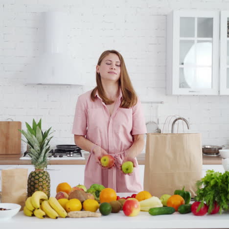 Happy woman unpacking healthy vitamins. Young female in the kitchen at home. Smiling housewife near the table with a lot of fresh fruit and vegetables. Diet lifestyle.