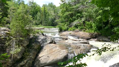 A-river-and-its-small-cascade-in-Ontario,-Canada,-wide-to-medium-tracking-shot