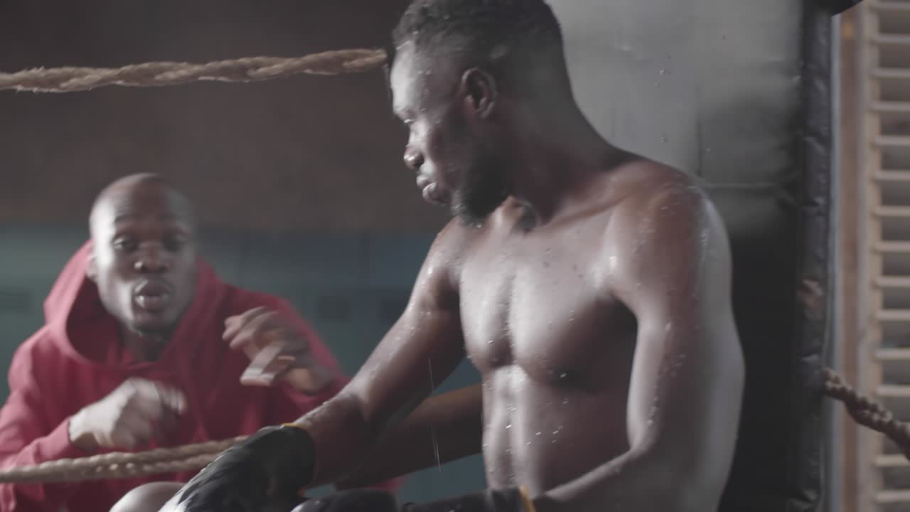 흑인 권투 선수 는 아마추어 경기 중 링 코너 에서 흥분 된 코치 의 말 을 듣고 있다