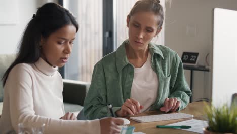 dos mujeres trabajando y analizando algo en la computadora en casa