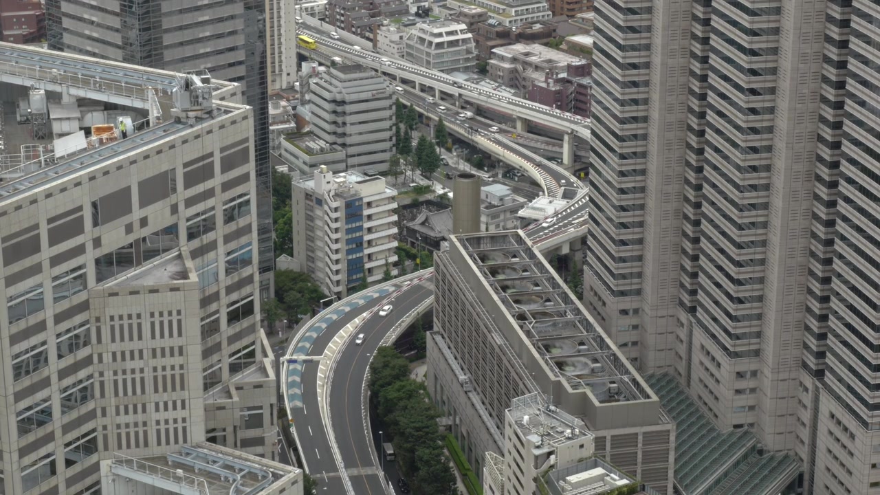 日本、東京、新宿の高層ビル群と近代的なオフィスビルを湾曲して貫く高架道路。広角ショット。