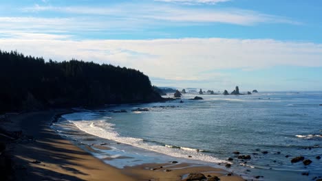 Impresionante-Toma-Aérea-De-Drones-De-La-Hermosa-Tercera-Playa-En-Forks,-Washington-Con-Grandes-Formaciones-Rocosas,-Rodeada-Por-Un-Bosque-De-Pinos-En-Los-Acantilados-Y-Arena-Dorada-En-Una-Cálida-Mañana-De-Verano