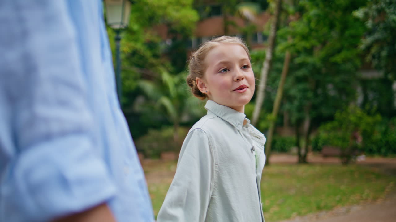 Small kid walking parent at lush green garden alley closeup. Little girl going