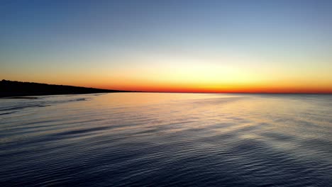 the ocean is calm and the sky is a beautiful orange color