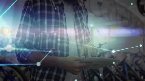 in bicycle shop, man using tablet with animation of digital network connections