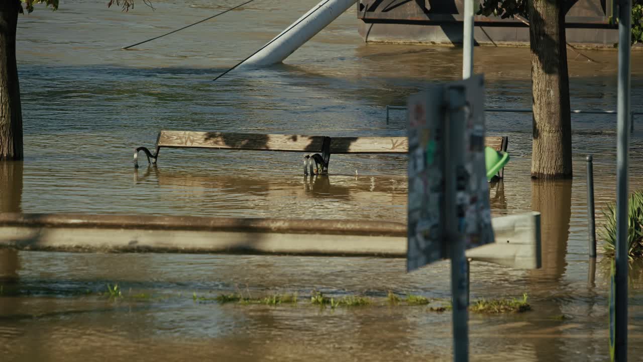 Partially submerged park bench and signage in floodwater during Budapest Flood 2024