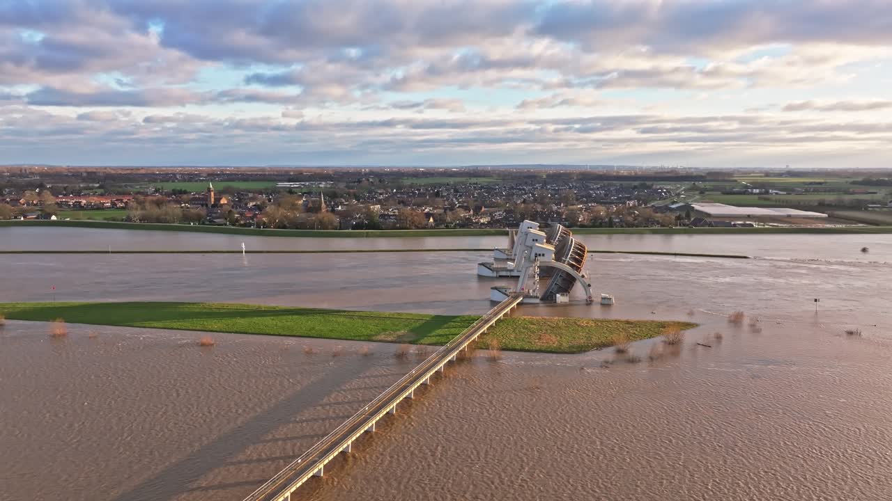 Aerial orbit drone shot to the right at the weir of Driel during high water levels with the doors open and with the town of Driel in the background