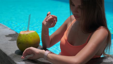 mujer relajándose en la piscina con coco y reloj inteligente