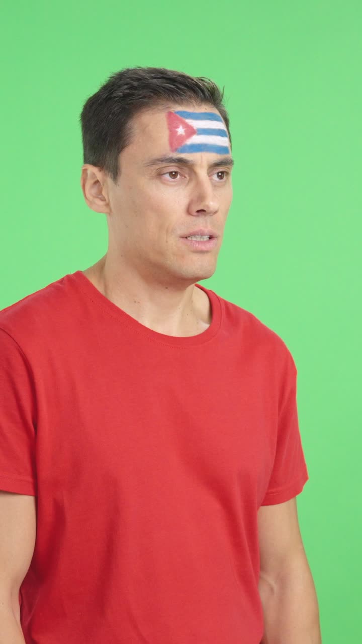 Happy man with cuban flag painted on face looking away