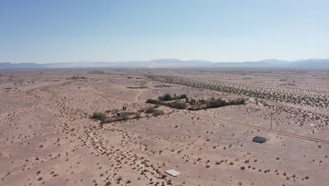 Toma-Aérea-Ascendente-Y-Panorámica-De-Casas-Dispersas-En-El-Desierto-En-El-árido-Desierto-De-Mojave-De-California