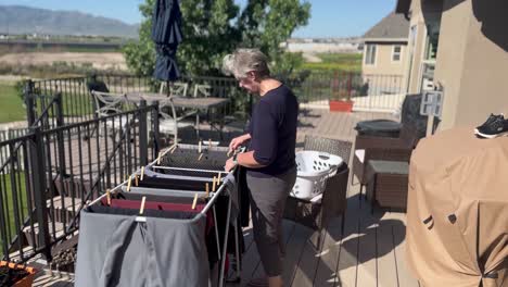 Mature-woman-hanging-laundry-on-a-rack-on-her-deck-or-porch