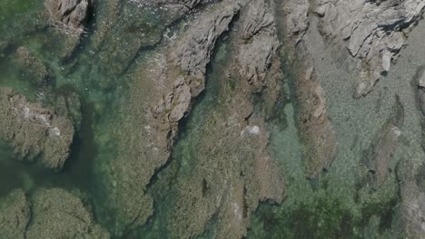 birds-eye-view close-up rocky beach clear green water waves summer cornwall overhead aerial seashore