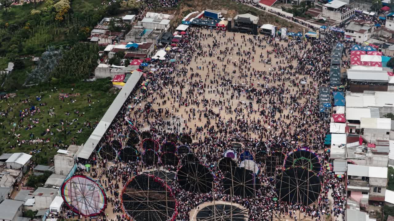 Top view of giant handmade kites surrounded by crowds at Sumpango festival
