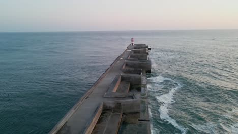 Aerial-flyOver-massive-sea-wall-Barra-do-Douro-at-dusk,-Porto-Portugal