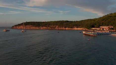 Aerial-birds-eye-view-tourist-with-jet-skis-ride-by-beach-on-caribbean-island-coastline-with-sunset