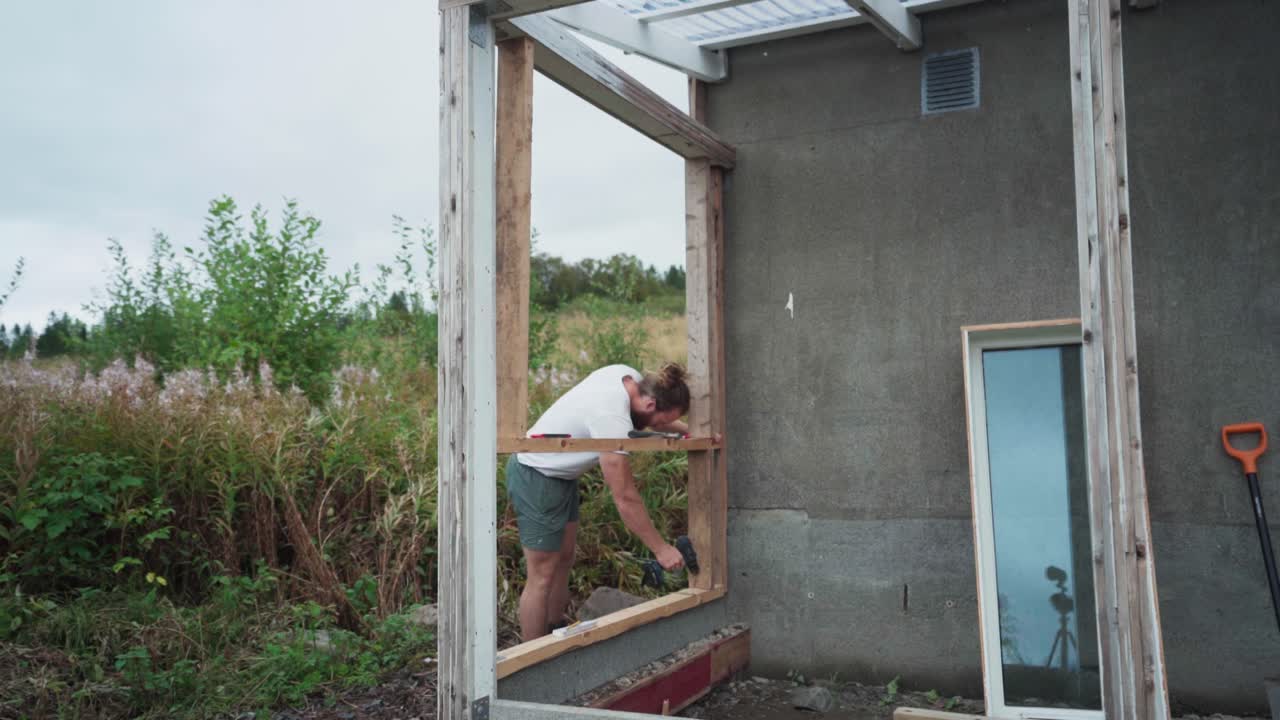 한 남자가 노르웨이의 트론델라그 카운티 인드레 포센에서 온실을 짓고 있습니다.