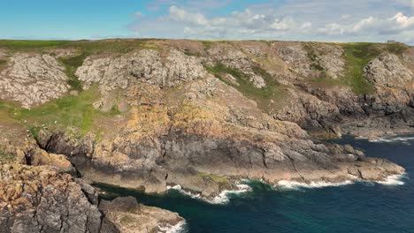 sweeping flight of cliffs along foot of cliffs and rocky shore on south coast of guernsey on bright sunny day