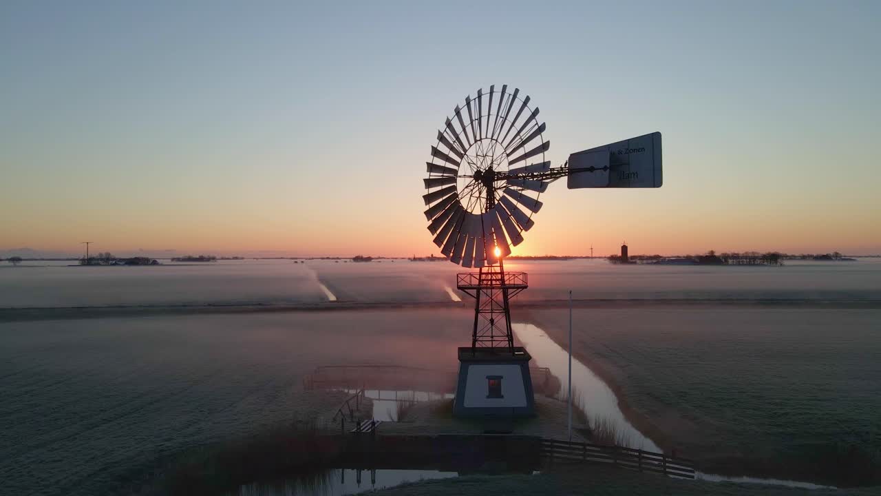 Scena di alba nebbiosa con mulino a vento d'epoca in un prato, vista drone, Friesland