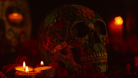 close up on still life of decorated skull surrounded by candles and flower petals celebrating mexican holiday of dia de muertos or day of the dead 3