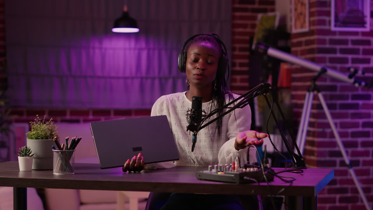 Woman vlogger influencer recording product review for laptop with professional audio equipment and microphone