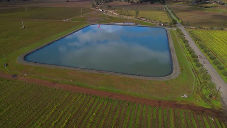 aerial of cloud reflections on vineyard water dam to reveal snow on mountains in the napa valley