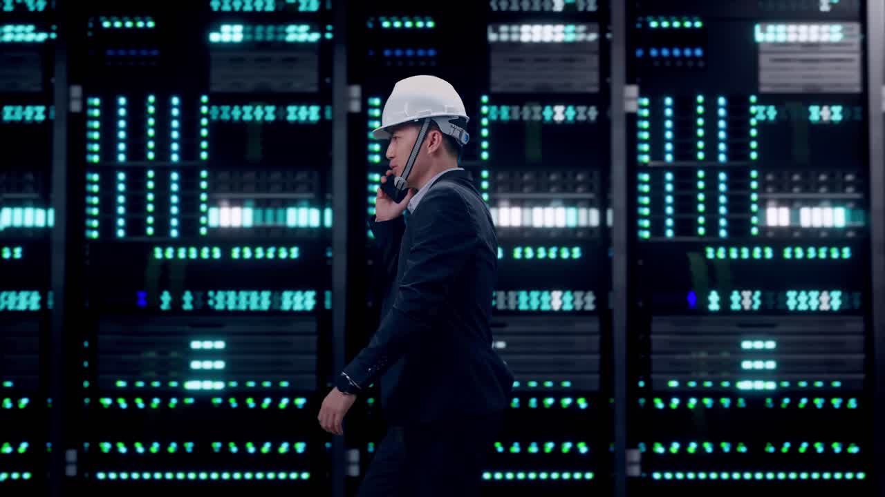 Side View of Asian Businessman Talking On Smartphone While Walking in Server Room Data Center