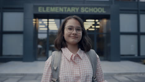 portrait smiling girl standing at school entrance. teenager looking camera.