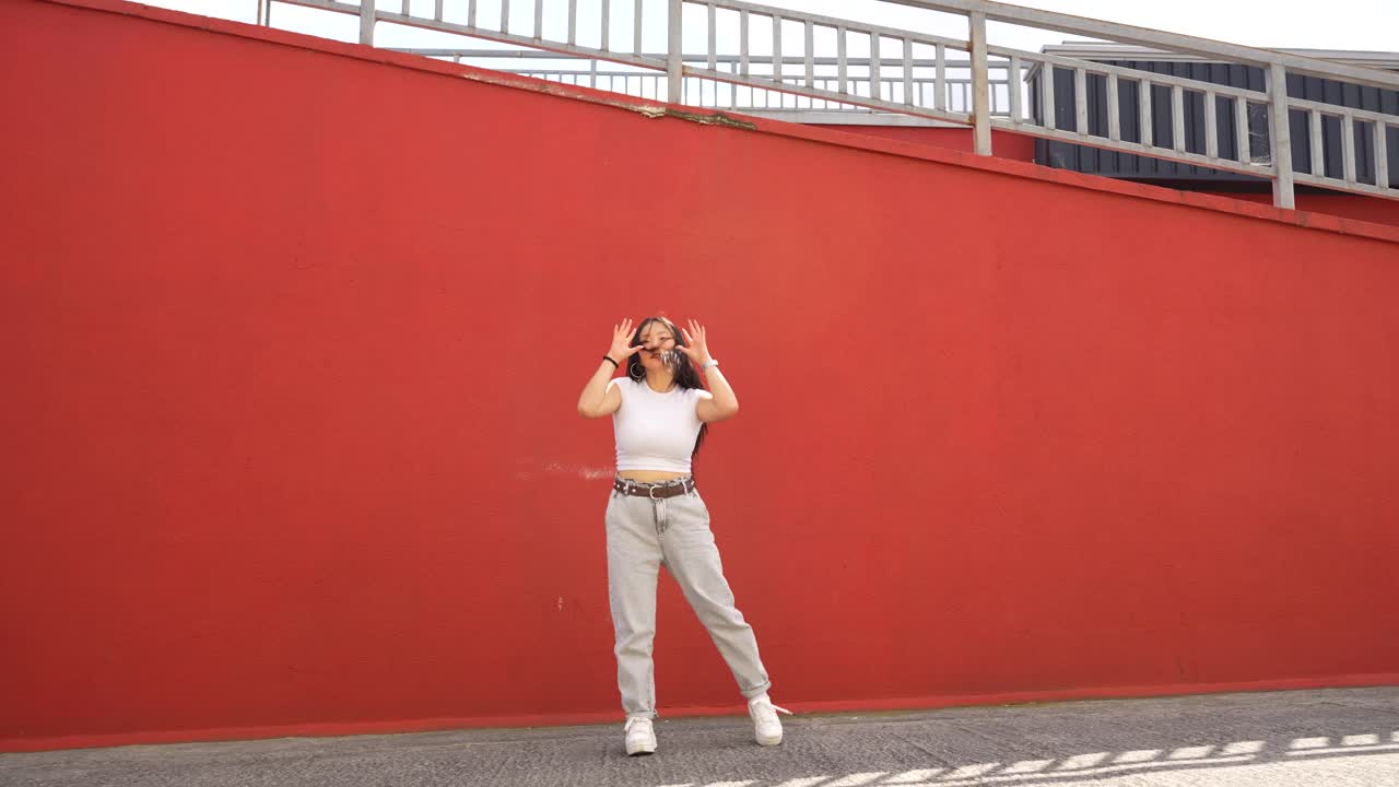Young woman posing in front of a red wall